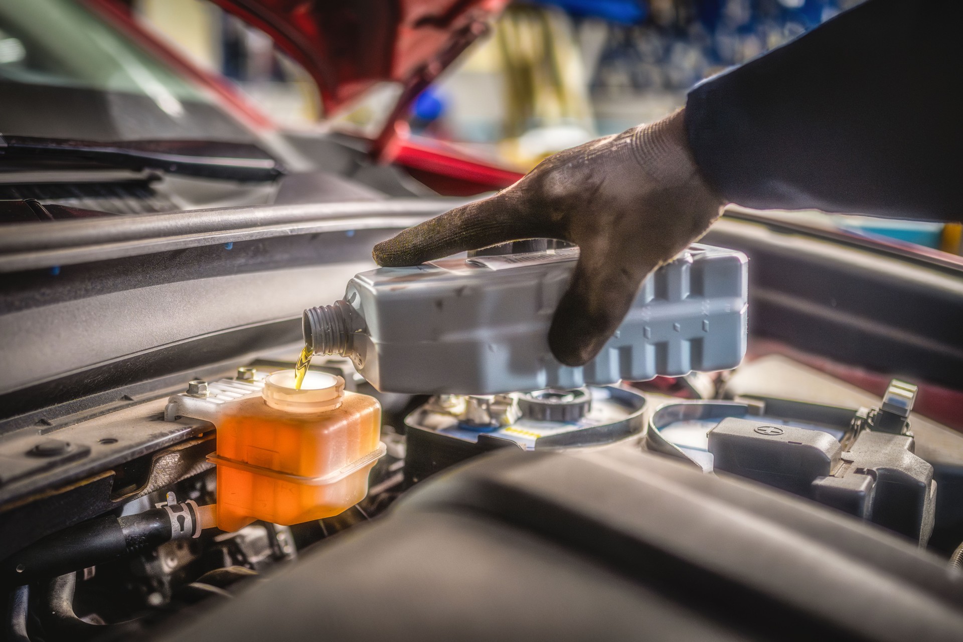 Mid Adult Mechanic Changing Car Oil in Workshop